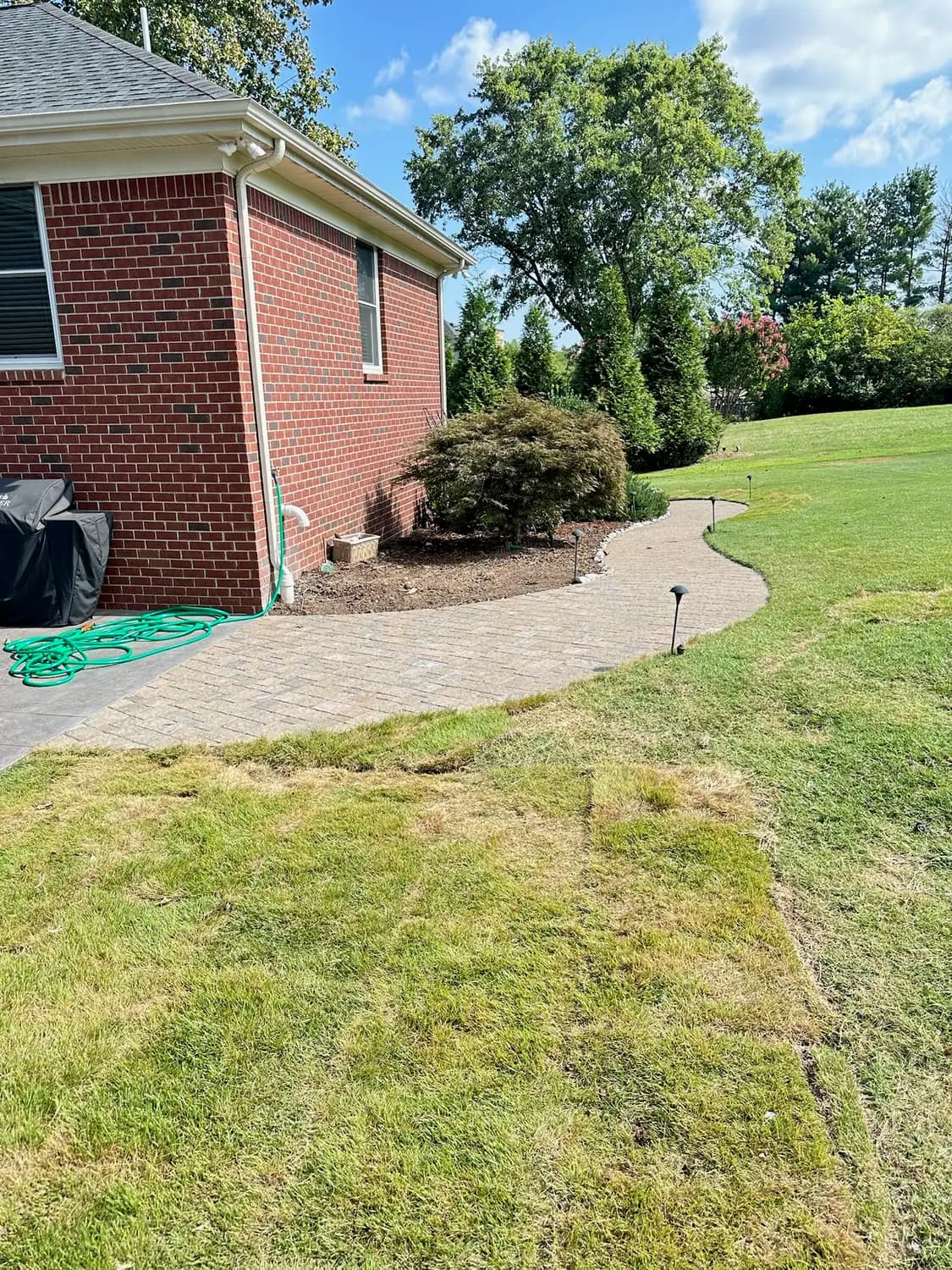 Curved paver walkway running alongside a home