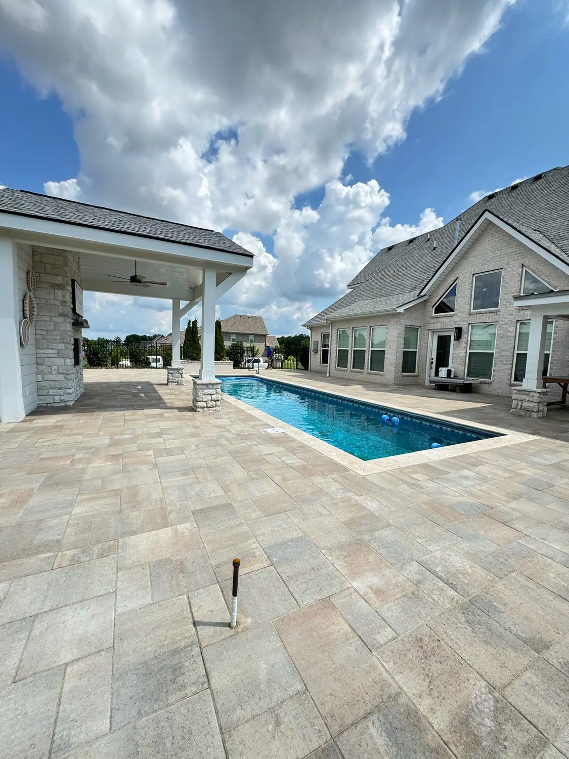 Travertine paver pool deck with a covered outdoor pavilion