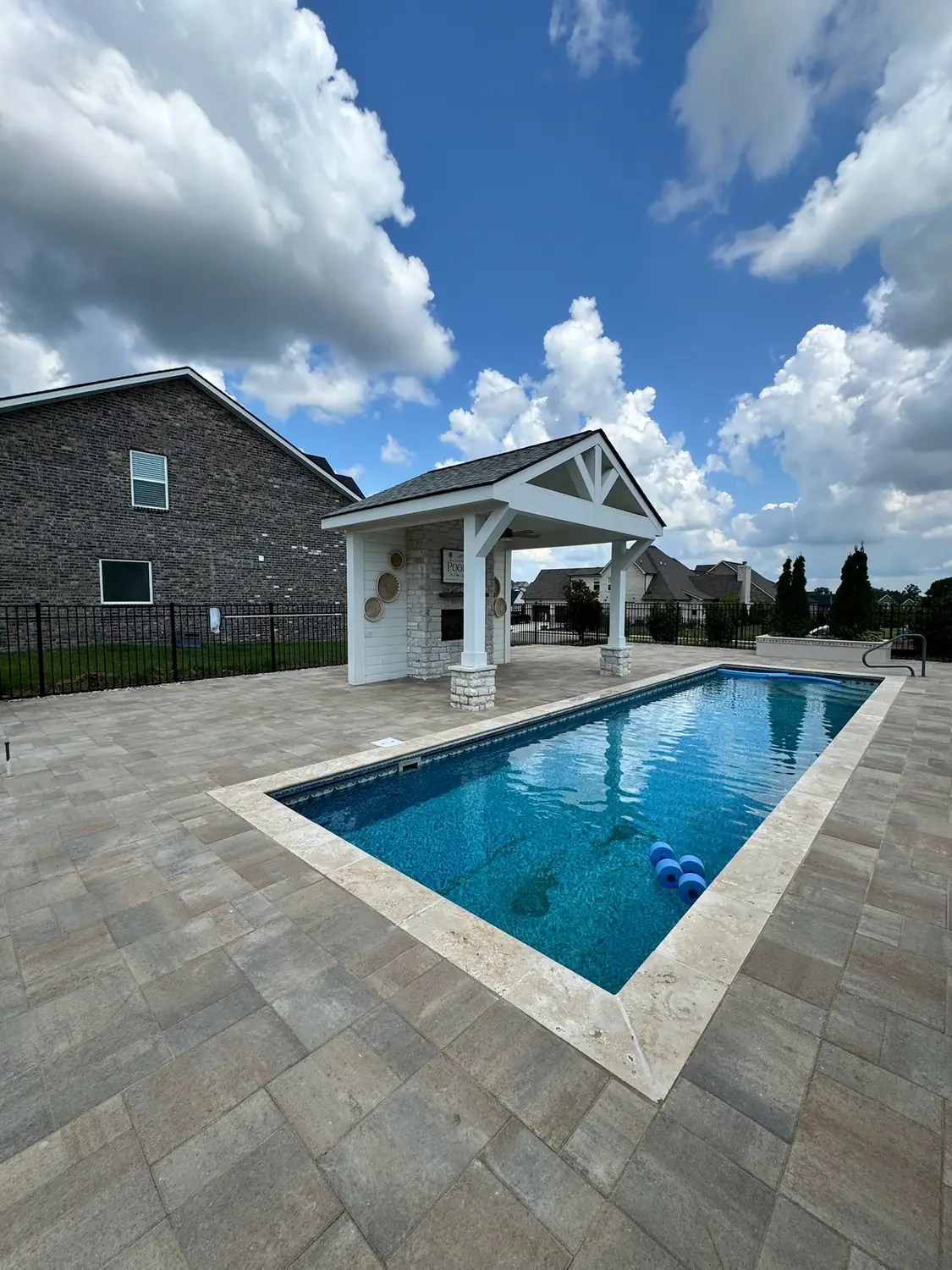 Resort-style pool with a wide paver deck and shade pavilion
