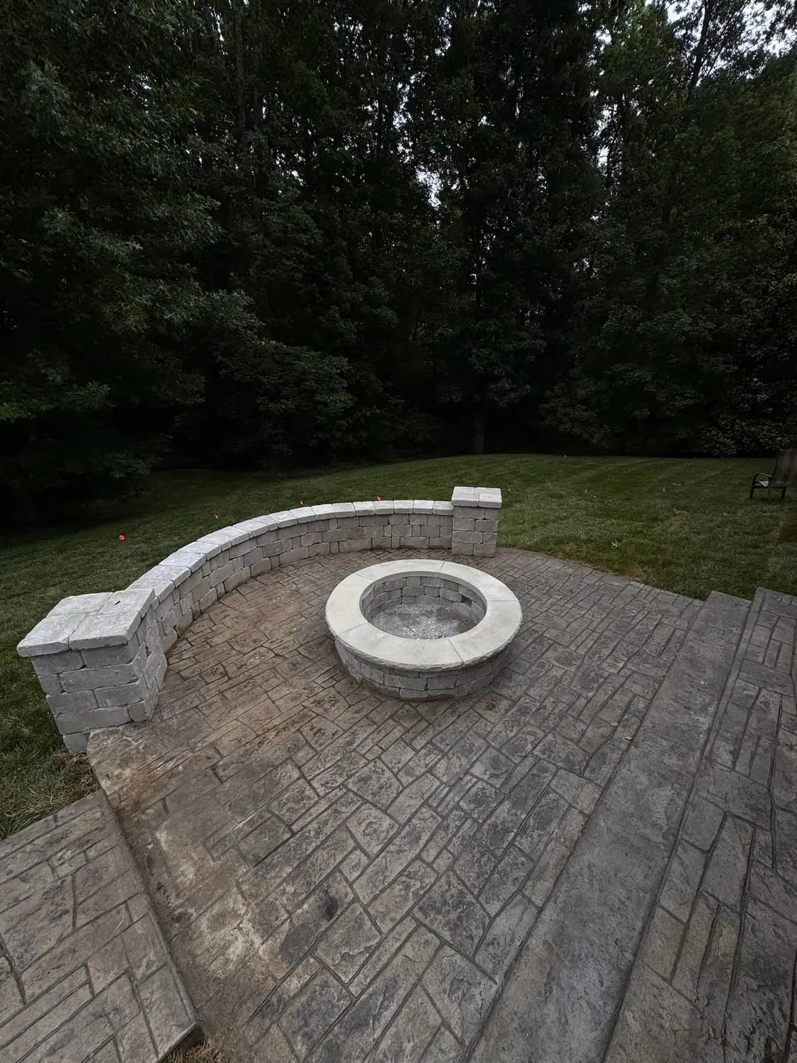 Stamped concrete patio with a fire pit and curved seat wall